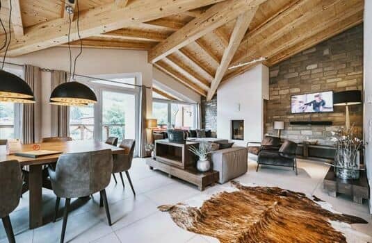 Open-plan living area with vaulted timber ceilings and stone fireplace