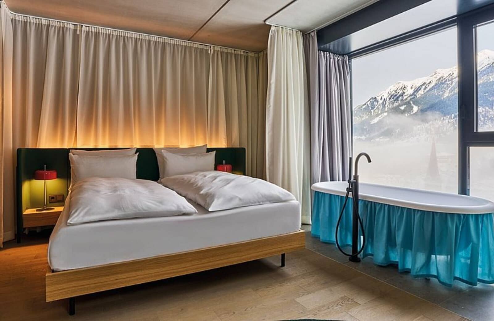 Primary bedroom with king bed and in-room soaking tub by mountain-view window