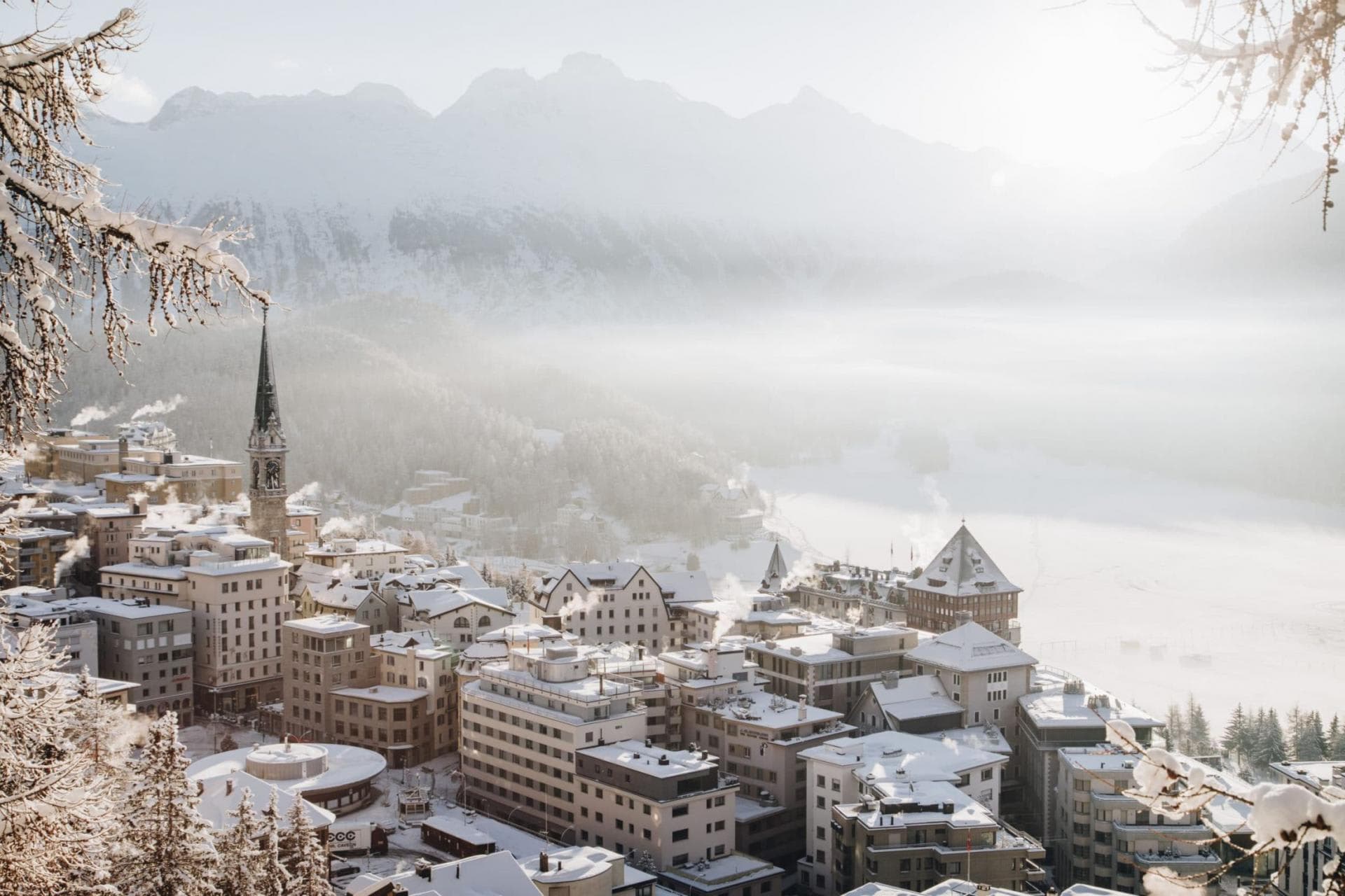 Aerial village view overlooking snow-capped peaks and valley fog