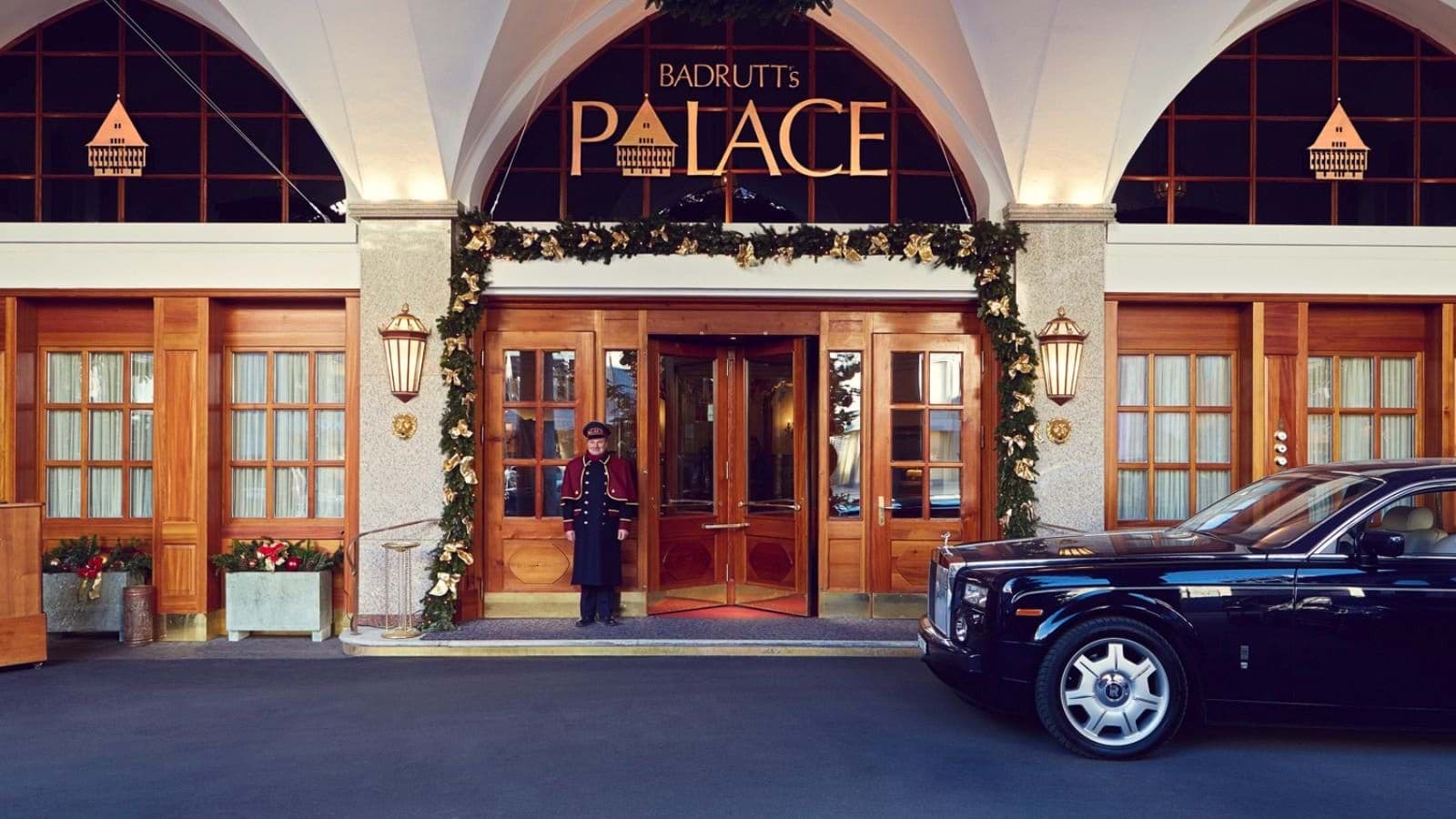Hotel entrance with revolving door, uniformed doorman, and Rolls-Royce chauffeur service