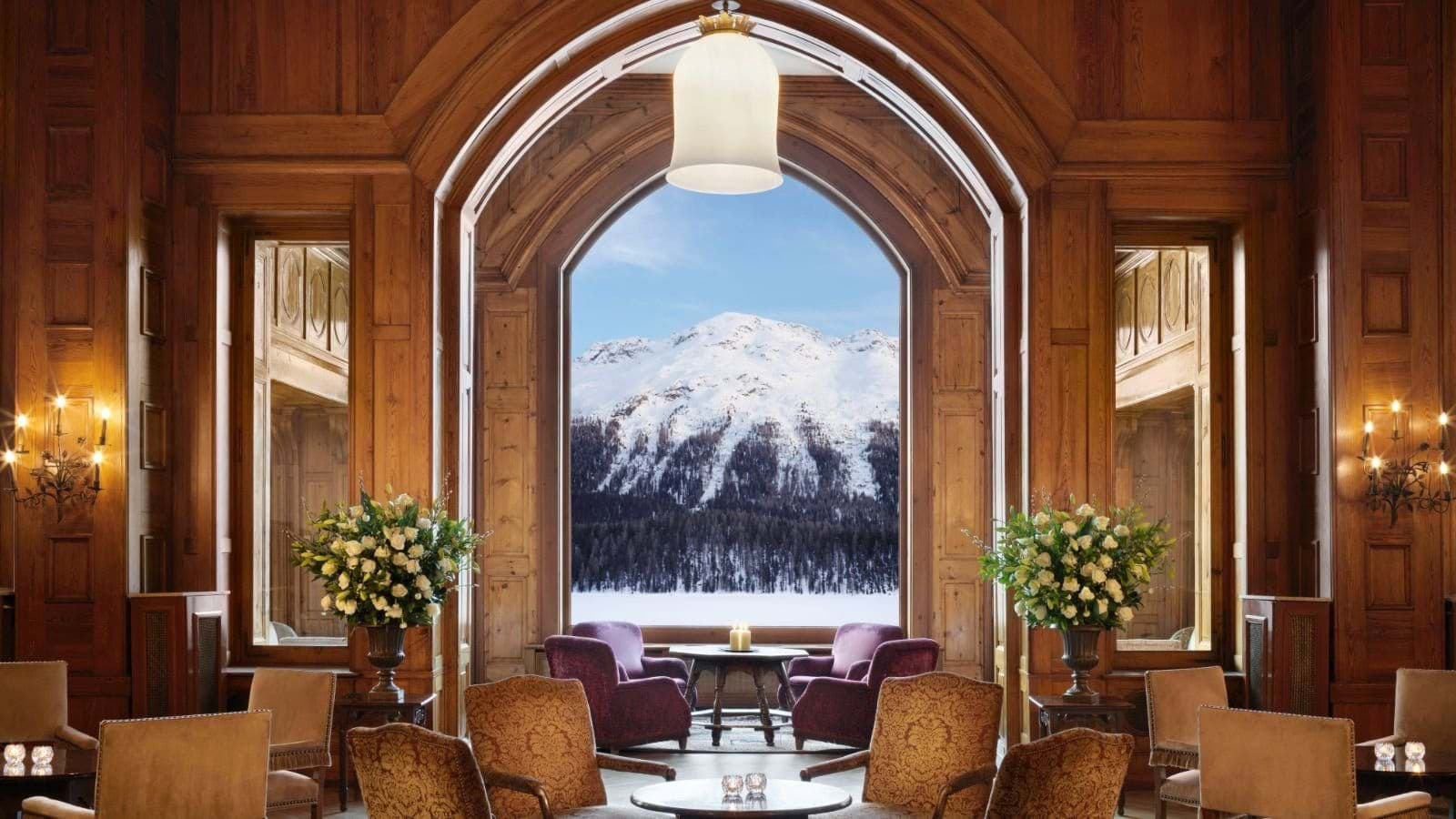 Lounge with wood paneling and arched window view of snow-capped mountains