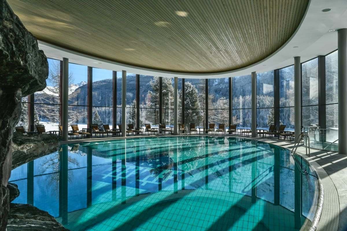 Indoor heated pool with floor-to-ceiling windows and mountain views