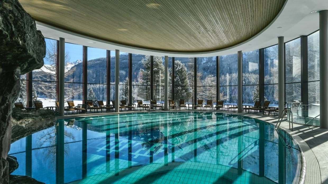 Indoor pool with floor-to-ceiling windows and alpine mountain views