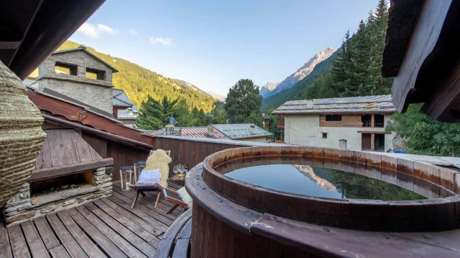 Private deck with wood-fired hot tub, outdoor fireplace, and alpine valley views