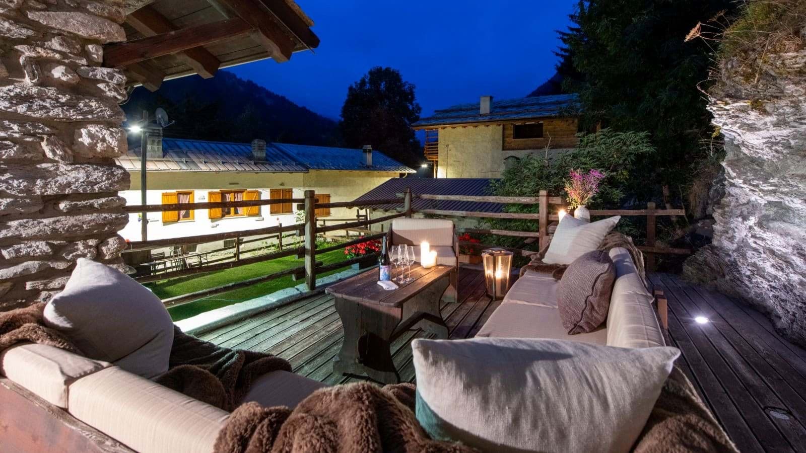 Stone-walled terrace with sectional seating, built-in lighting, and mountain village views