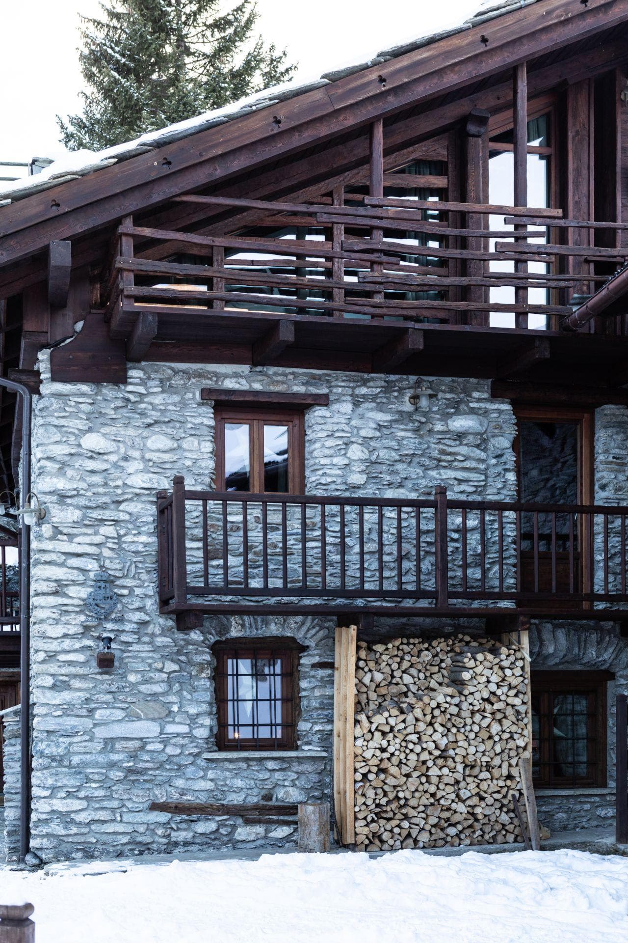 Stone chalet exterior with private balconies and firewood storage