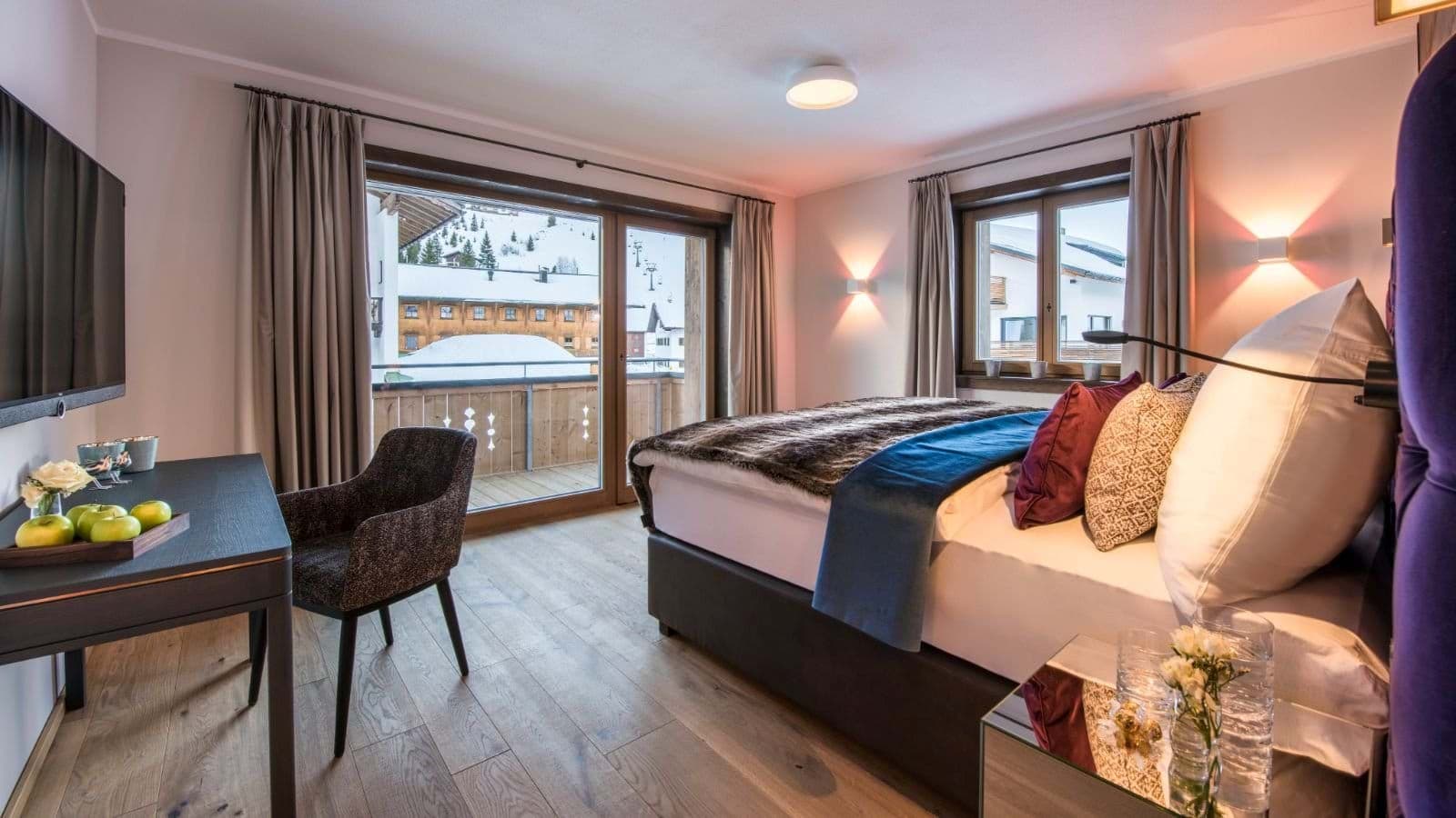 King bedroom with work desk and balcony overlooking ski slopes