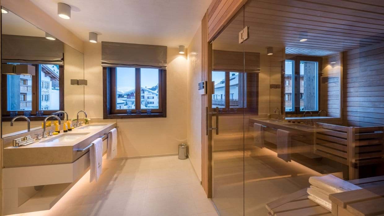 Dual vanity bathroom with glass-walled sauna and mountain views