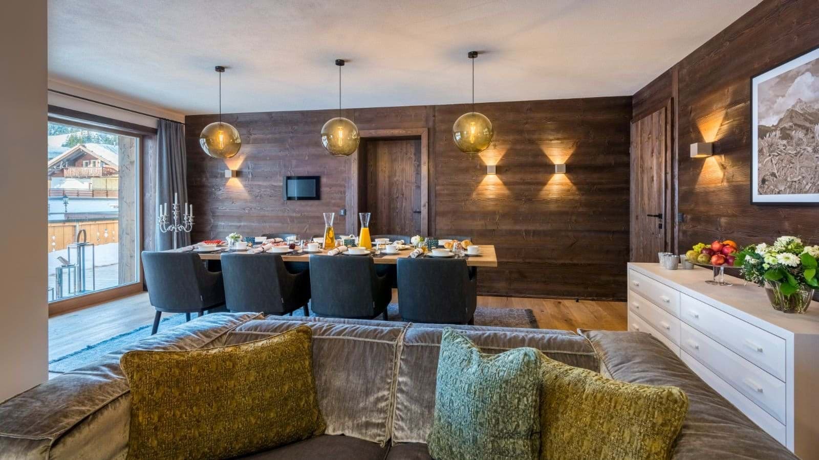 Dining table seats 8; wood-paneled walls and terrace access