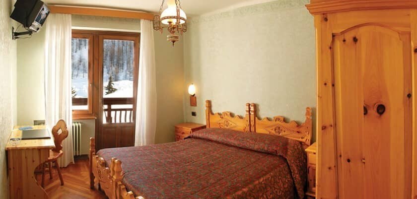 Guest bedroom with carved wood furniture, desk, and balcony access