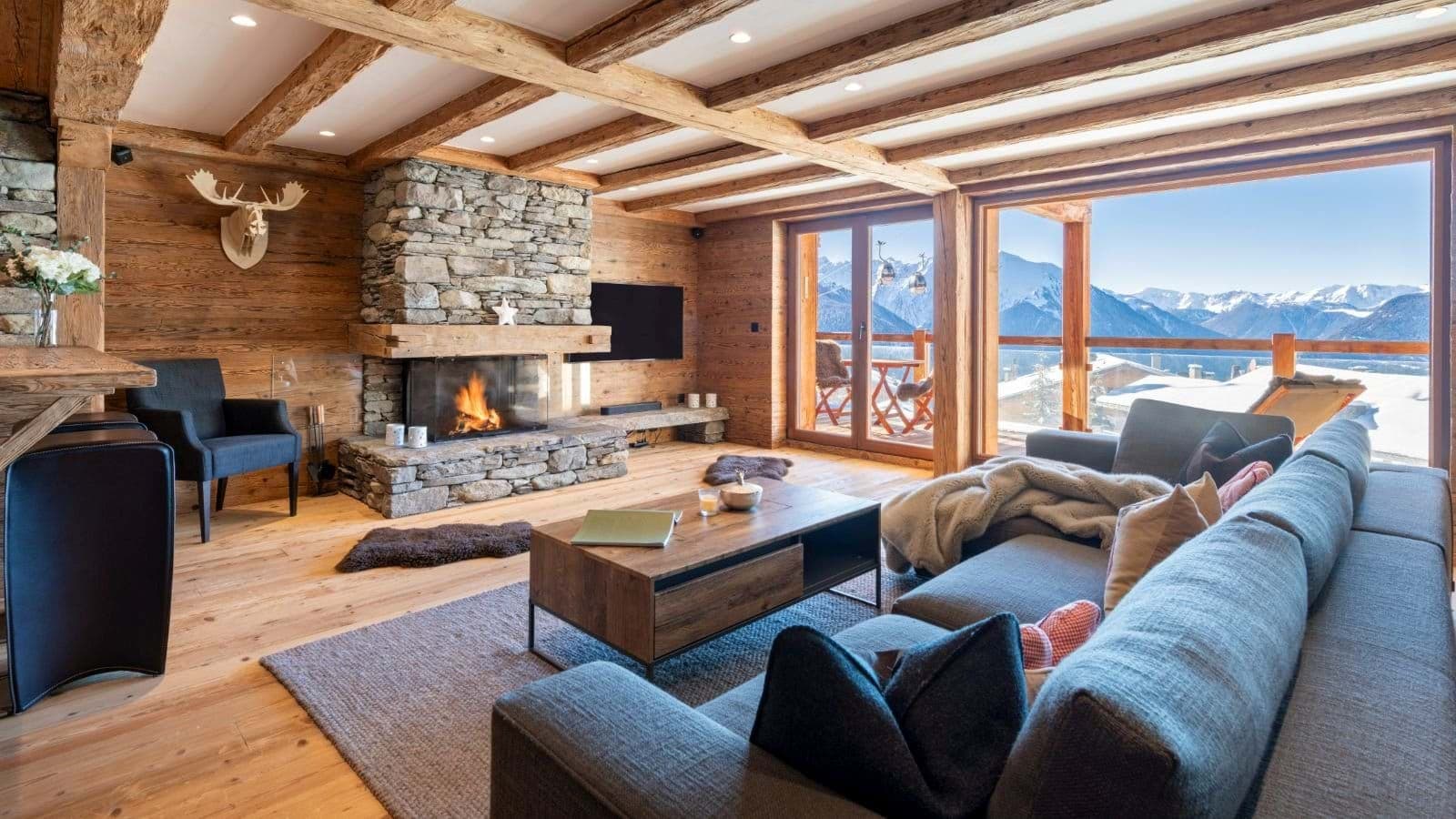 Living area with stone fireplace and floor-to-ceiling mountain views