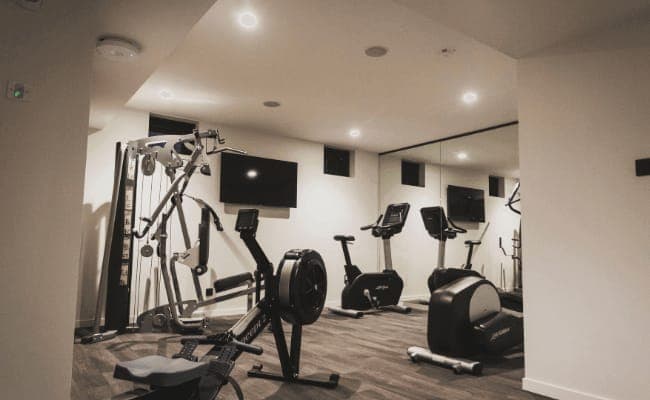 Private gym with Concept2 rower, Life Fitness bikes, and wall-mounted TV