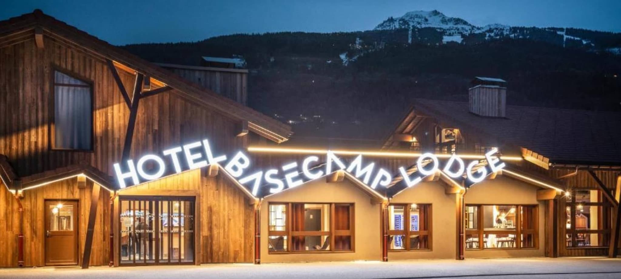 Basecamp Lodge exterior at dusk with mountain and ski slope views