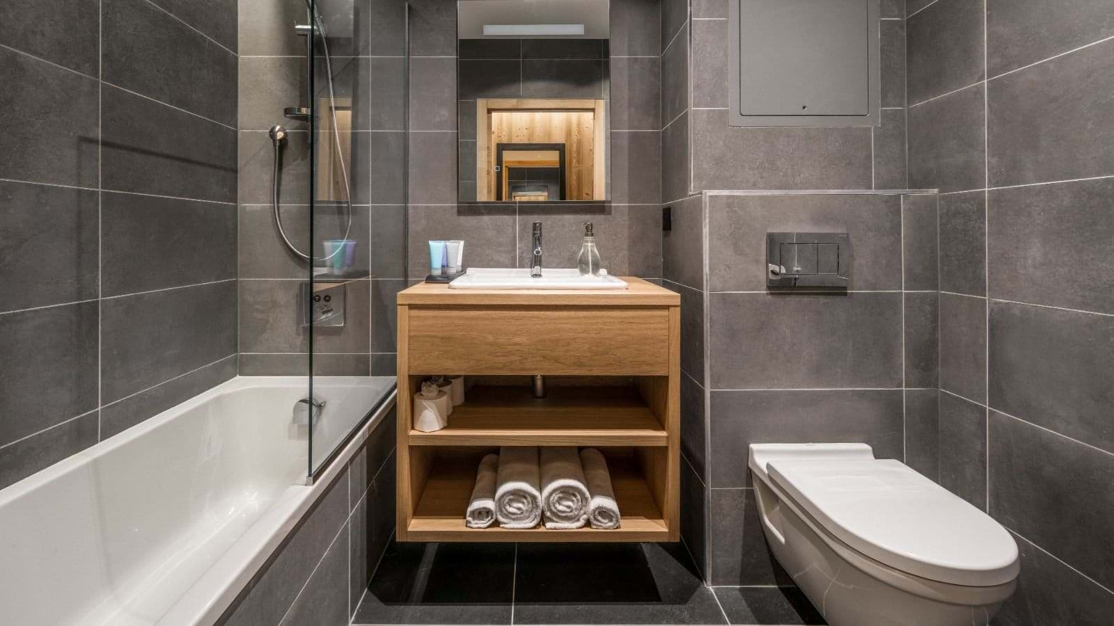 Bathroom with soaking tub, glass partition, and floating wood vanity