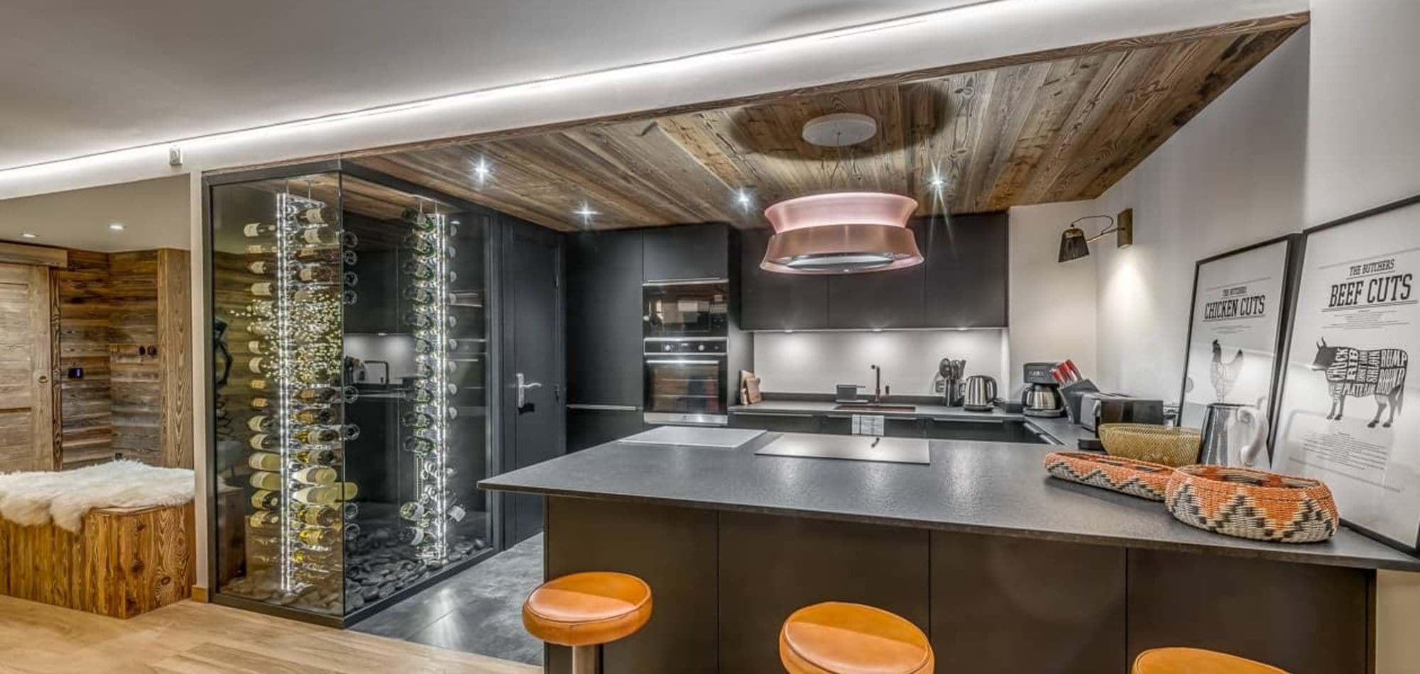 Kitchen with island seating and floor-to-ceiling glass wine cellar