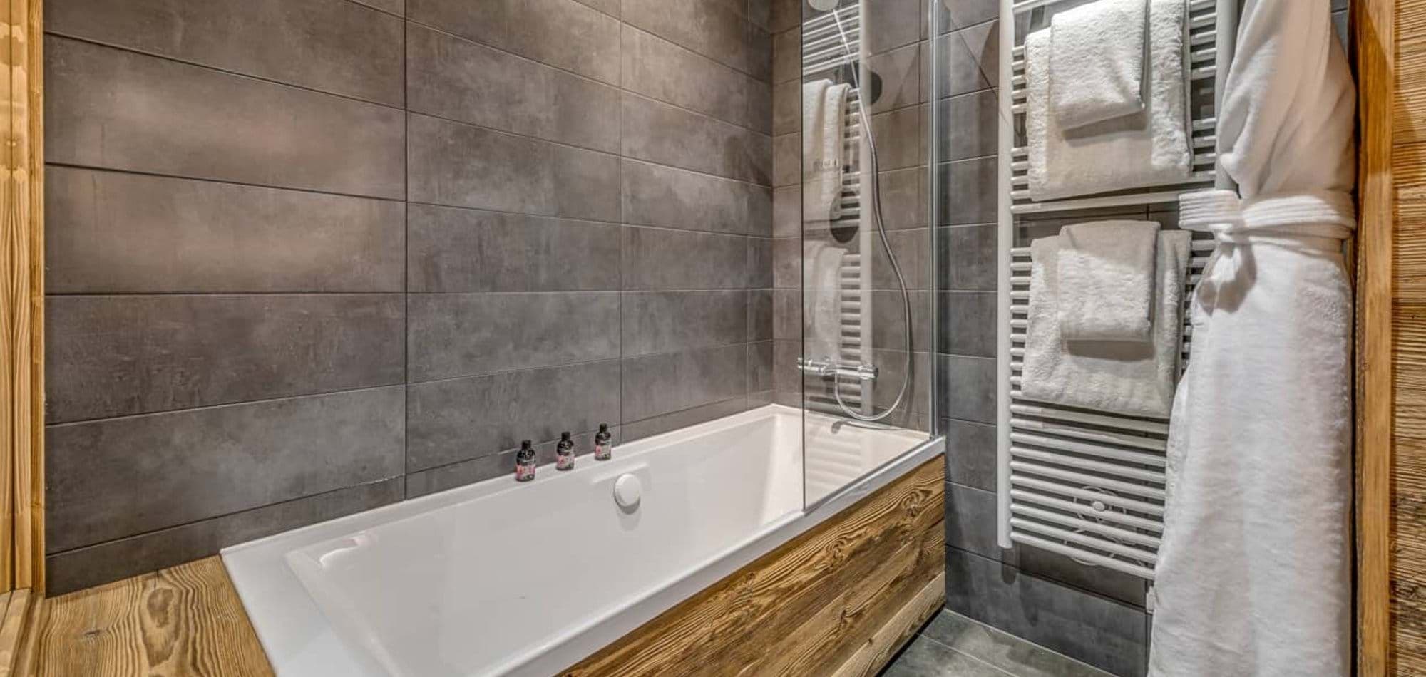 Bathroom with soaking tub, glass rain shower, and heated towel rack