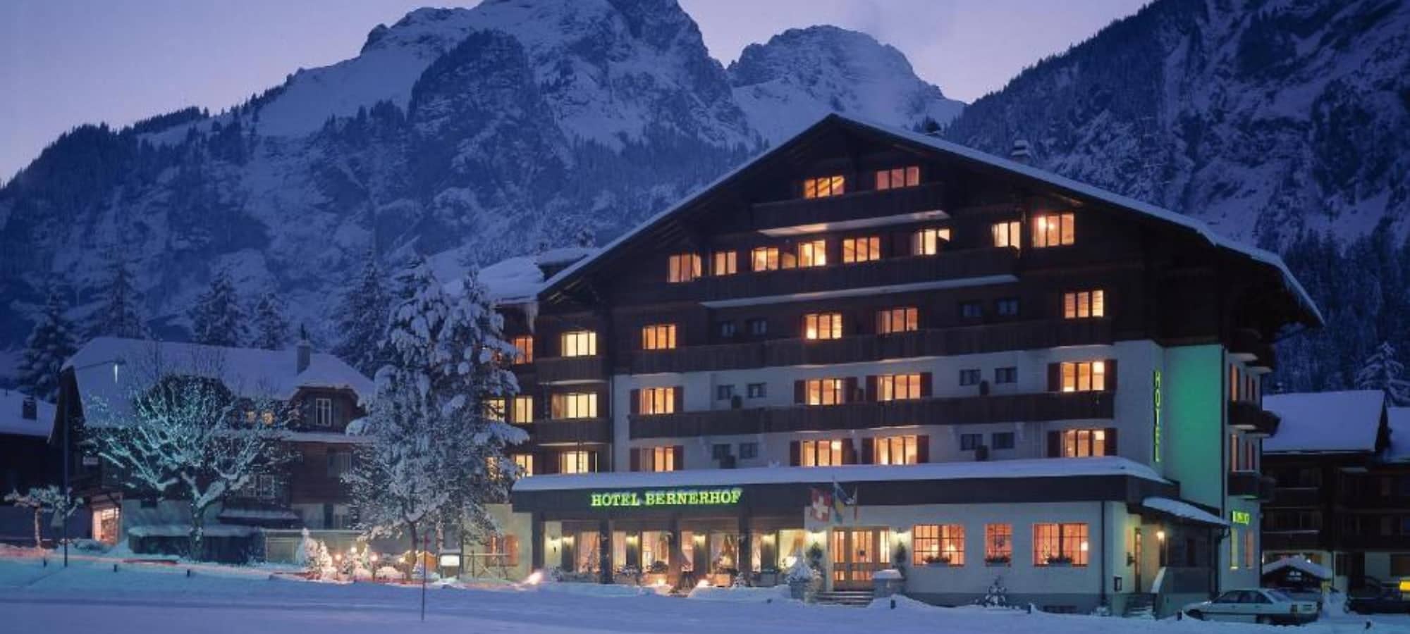 Hotel exterior at dusk with private balconies and mountain backdrop