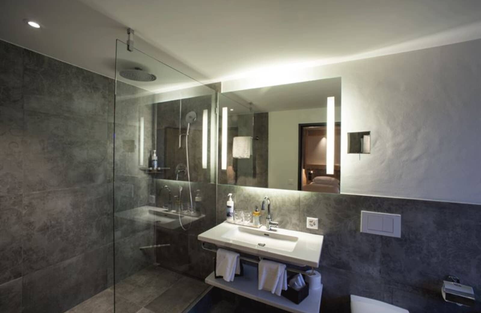 Bathroom with walk-in rainfall shower and backlit vanity mirror