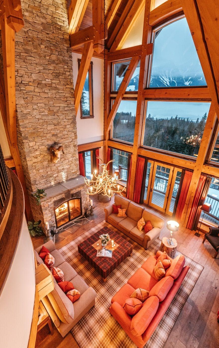 Great room with wood-burning stone fireplace and floor-to-ceiling mountain views