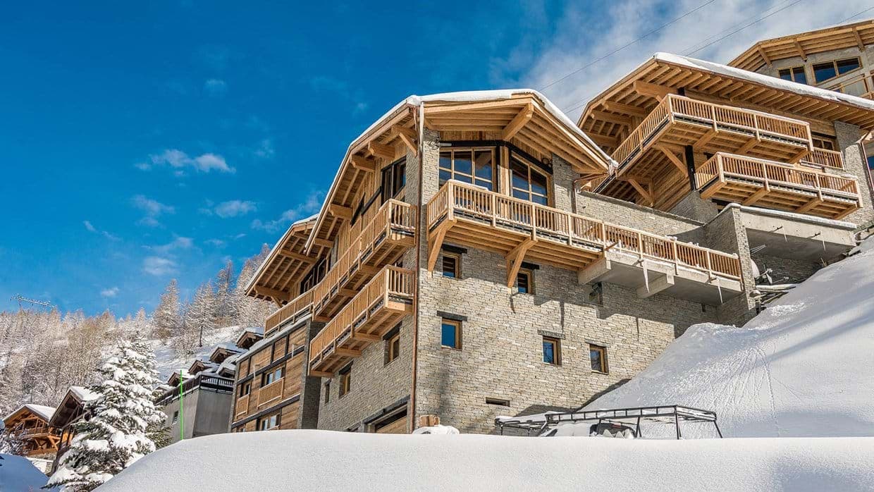 Ski-in ski-out chalet exterior with private balconies and stone masonry