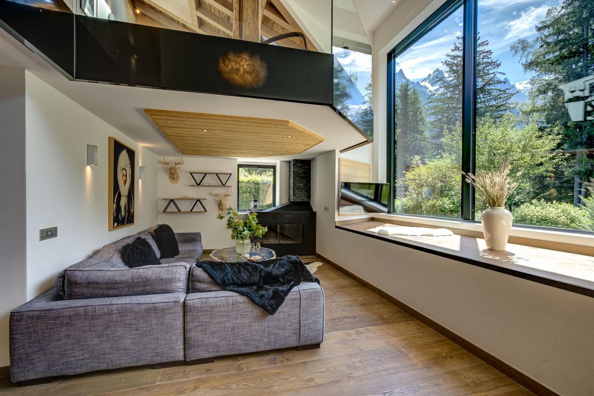 Living room with floor-to-ceiling mountain views and corner fireplace