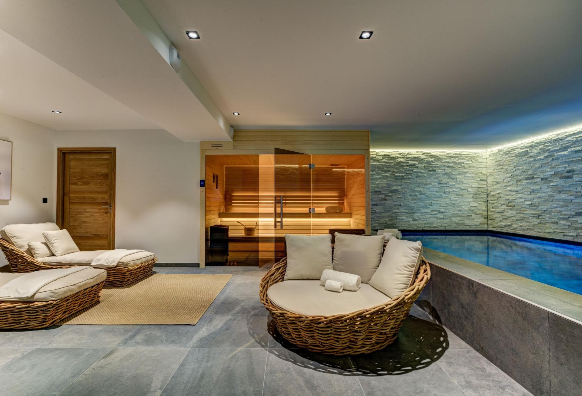 Private spa area with indoor pool, glass-fronted sauna, and wicker lounge seating