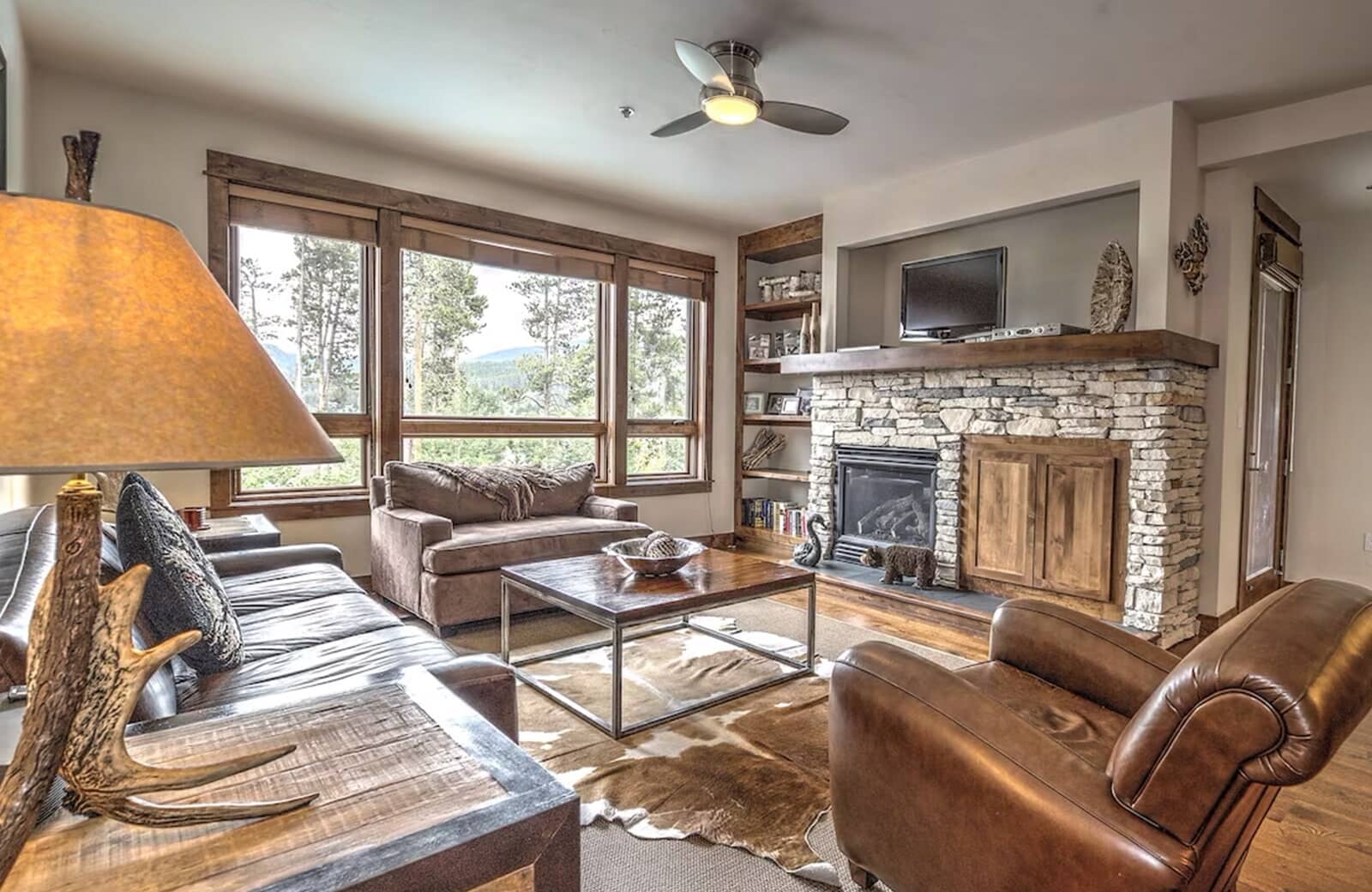 Living area with stone gas fireplace and forest views