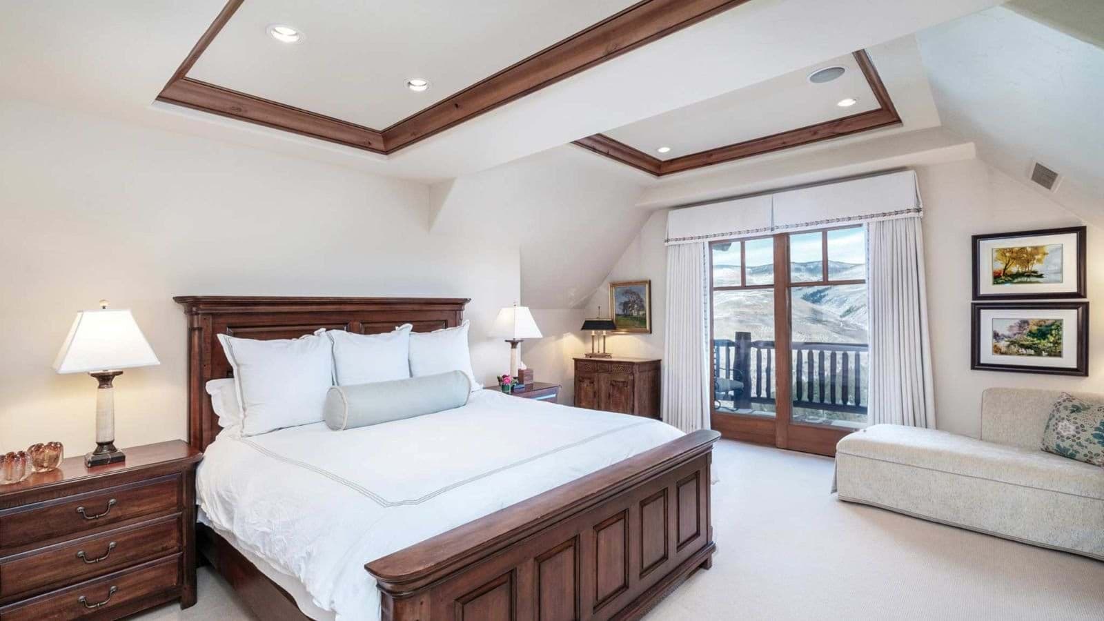 Primary bedroom with king bed, tray ceiling, and private balcony access