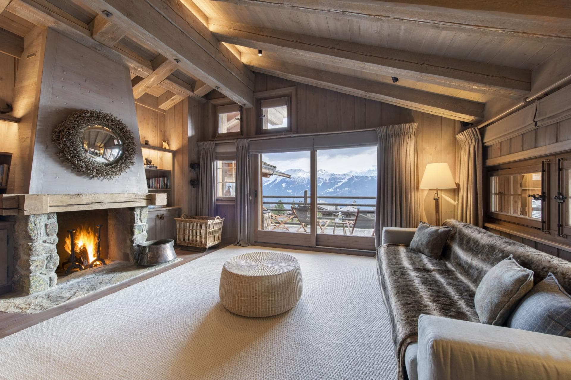 Living room with wood-burning stone fireplace and mountain-view balcony
