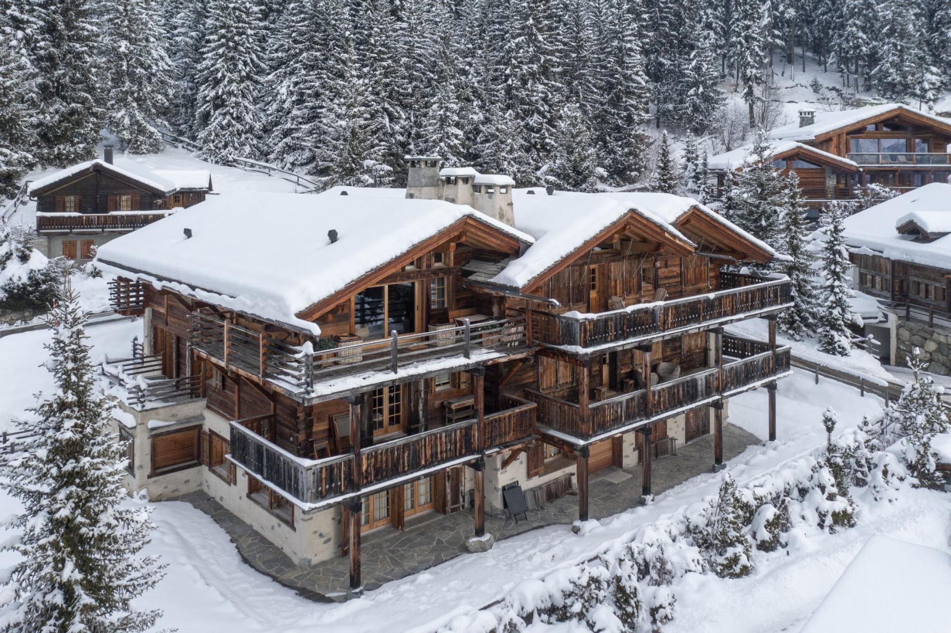 Three-story timber chalet with wraparound balconies set in snowy pine forest