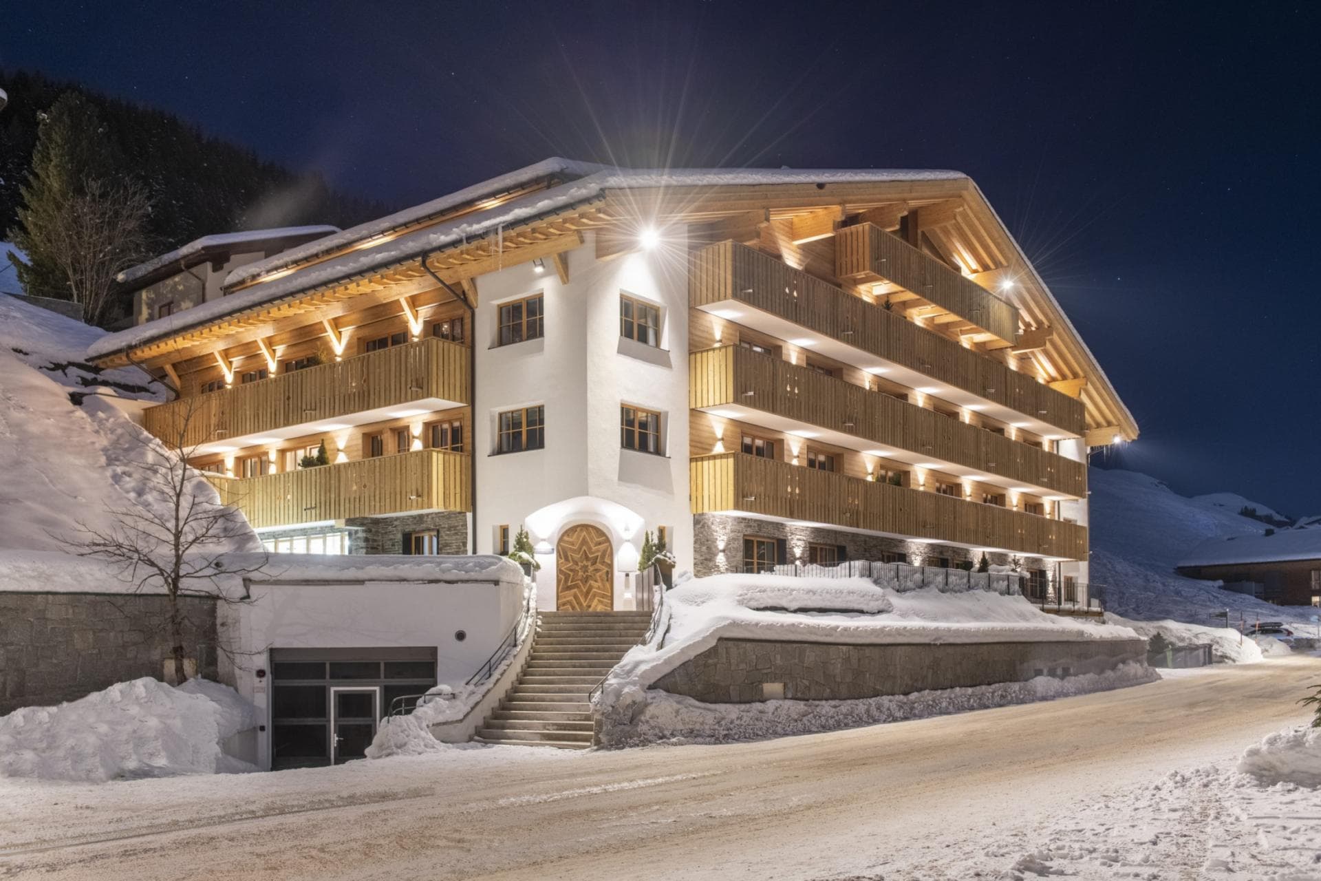 Alpine chalet exterior with heated roof eaves and underground garage entrance