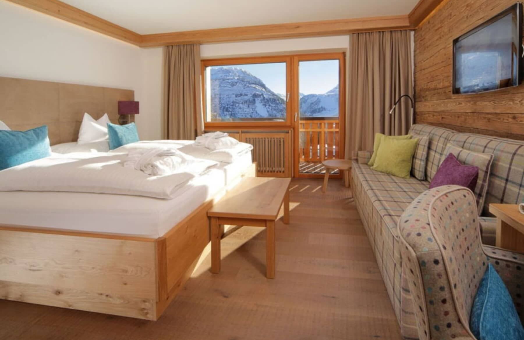 Bedroom with king bed, mountain-view balcony, and sofa seating area