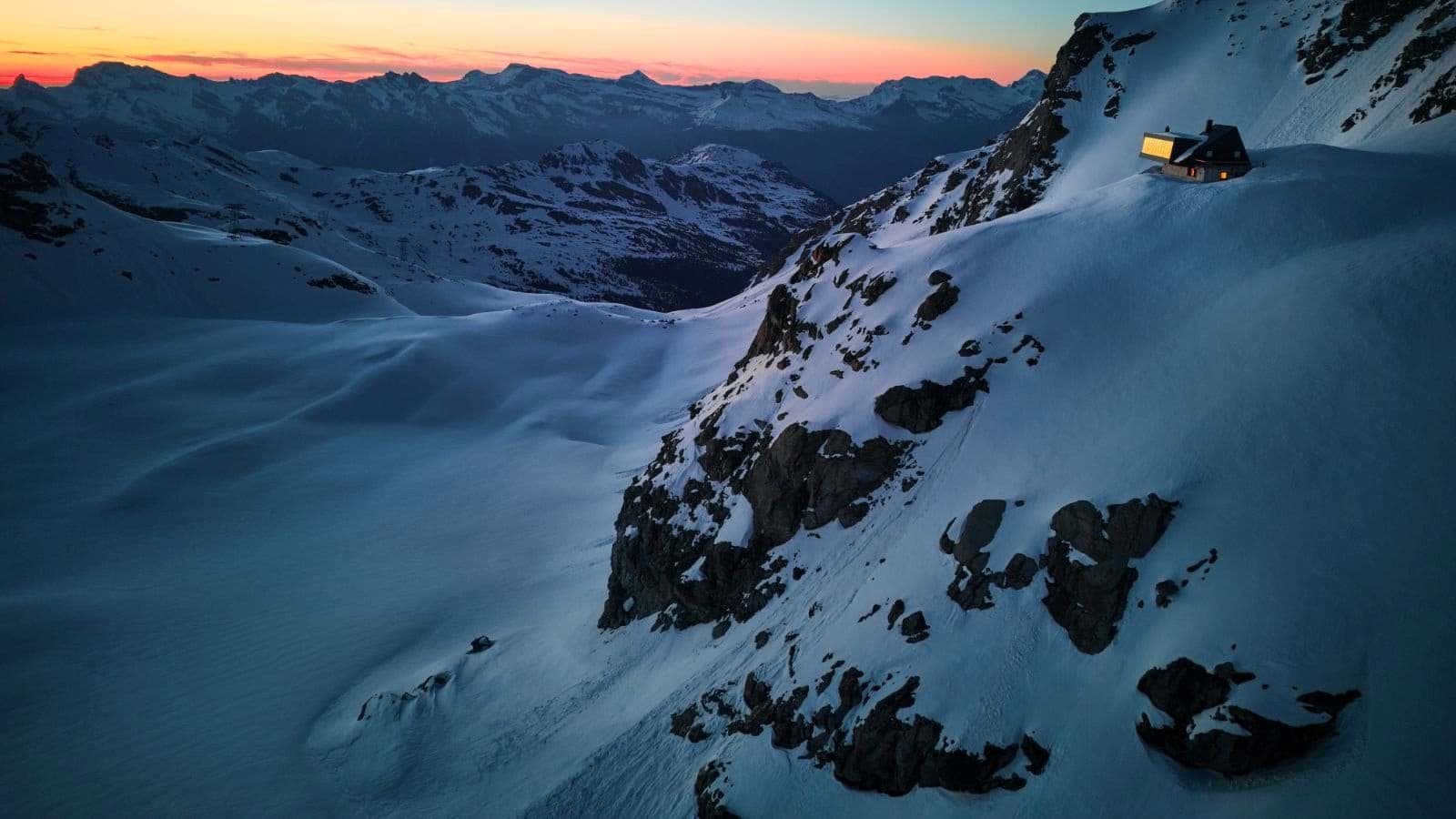 Ski-in cabin exterior with panoramic mountain range views at sunset