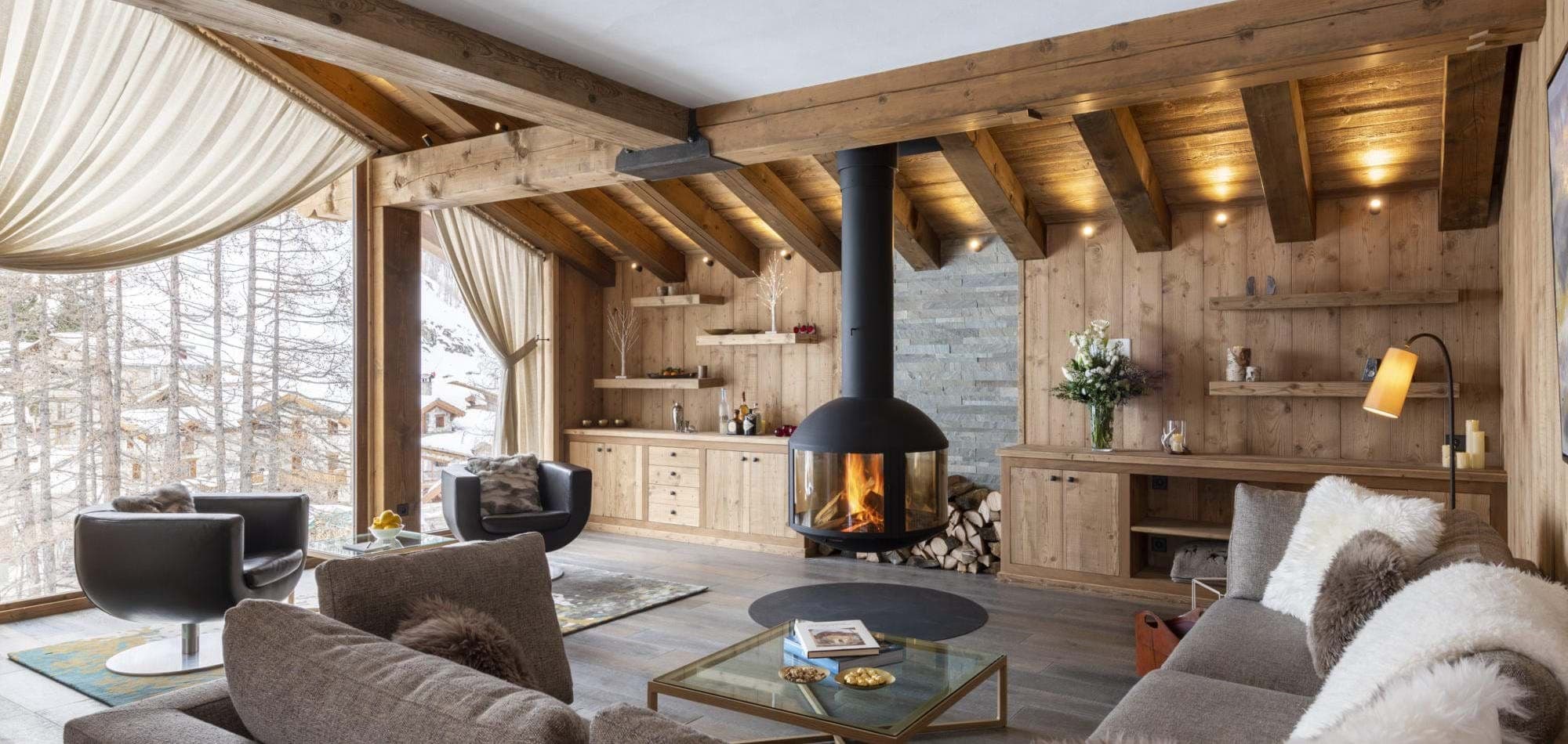 Living area with 360-degree suspended fireplace and snow-covered village views