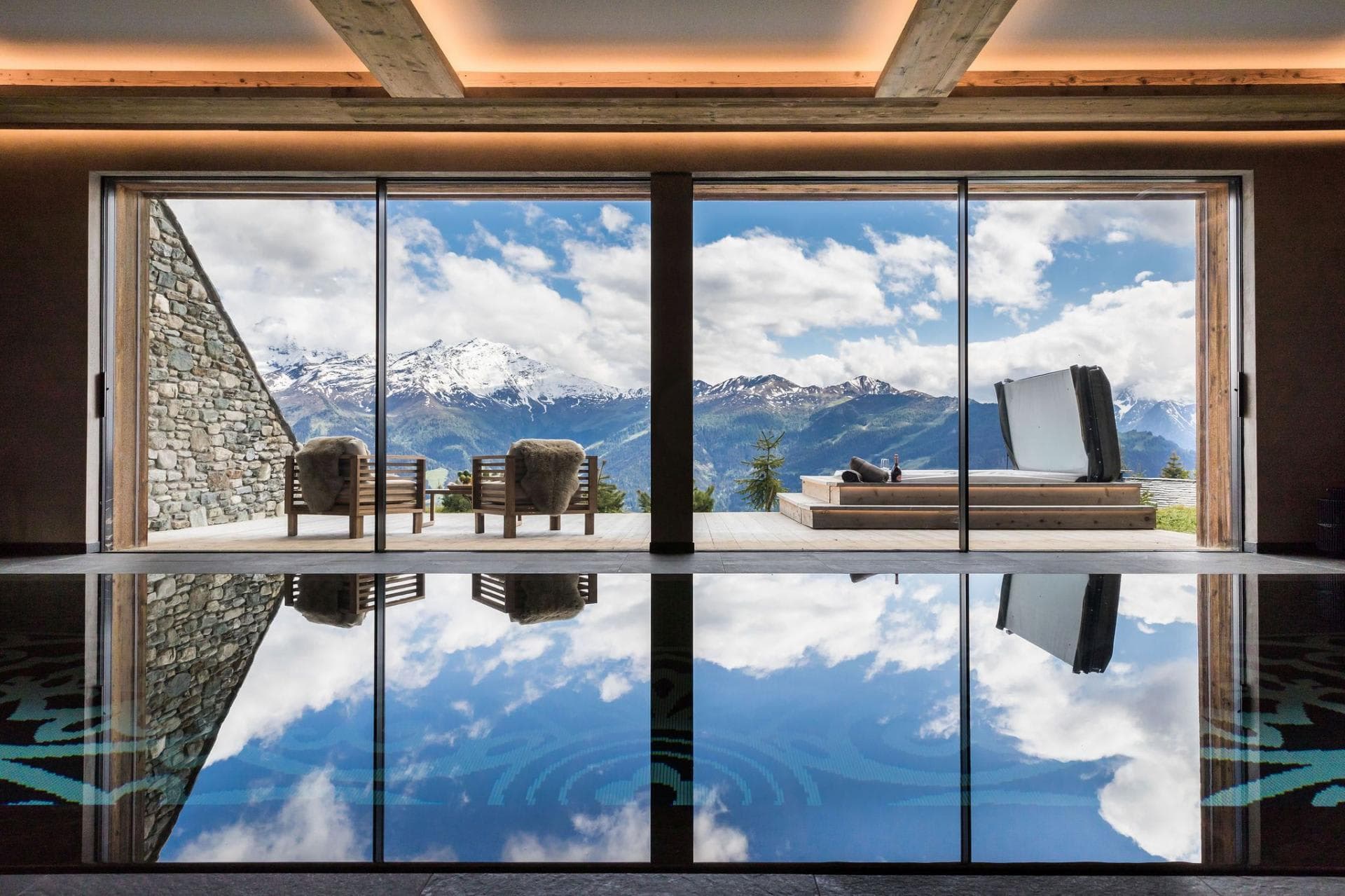 Indoor pool and outdoor deck with hot tub and mountain views