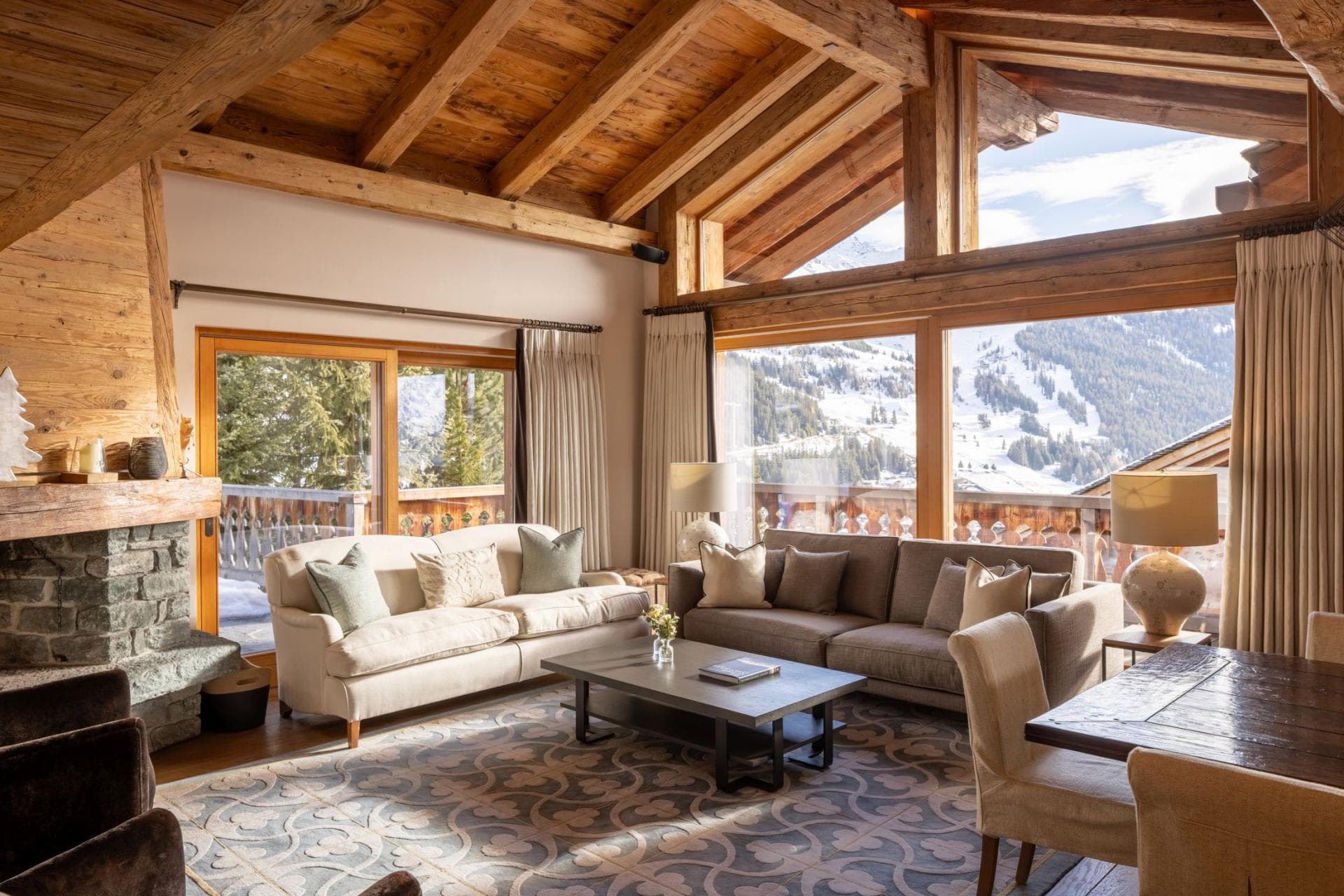 Living area with stone fireplace and floor-to-ceiling ski run views