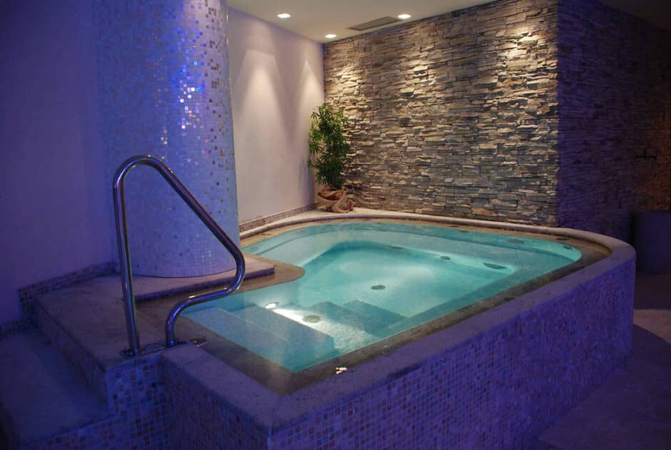 Indoor hot tub with metal handrail and mosaic tile finish