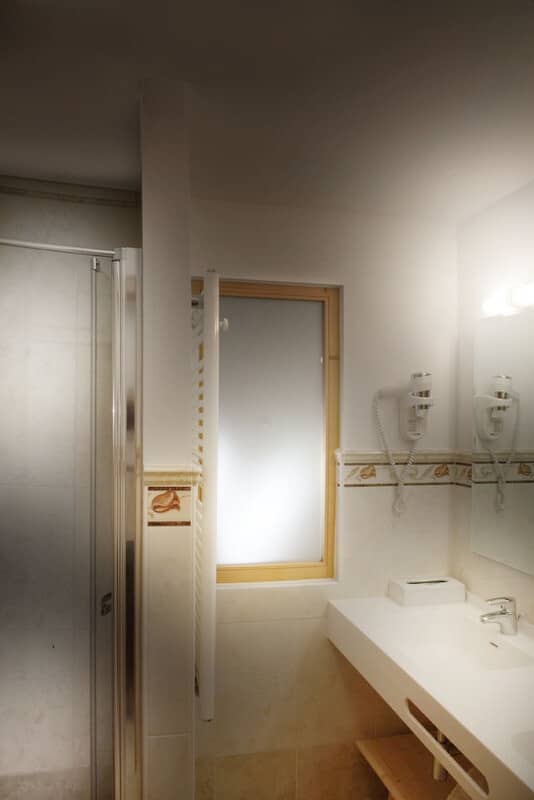 Bathroom featuring walk-in shower, wall-mounted hairdryer, and heated towel rack