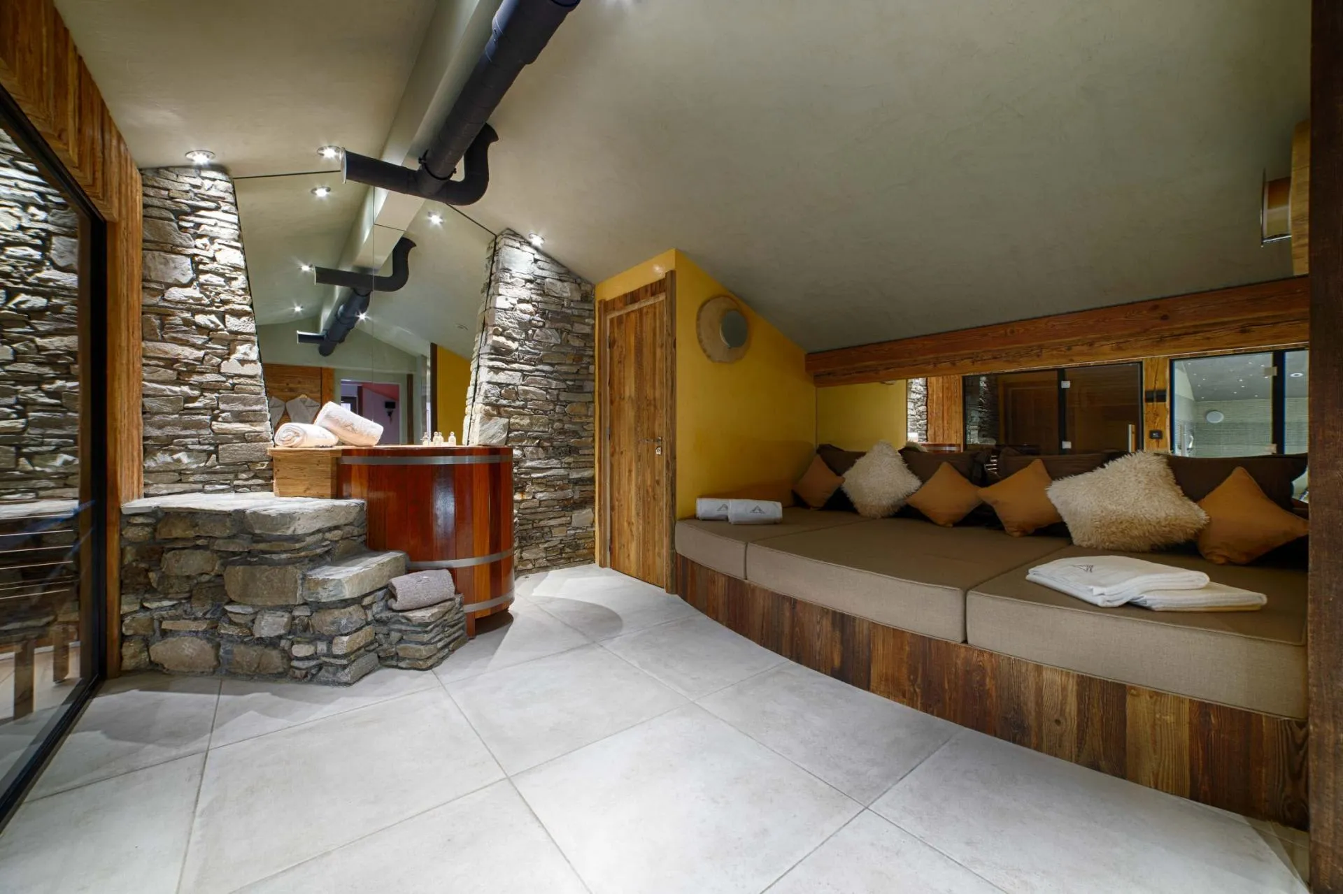 Wellness area with wooden plunge pool, built-in daybed, and sauna access