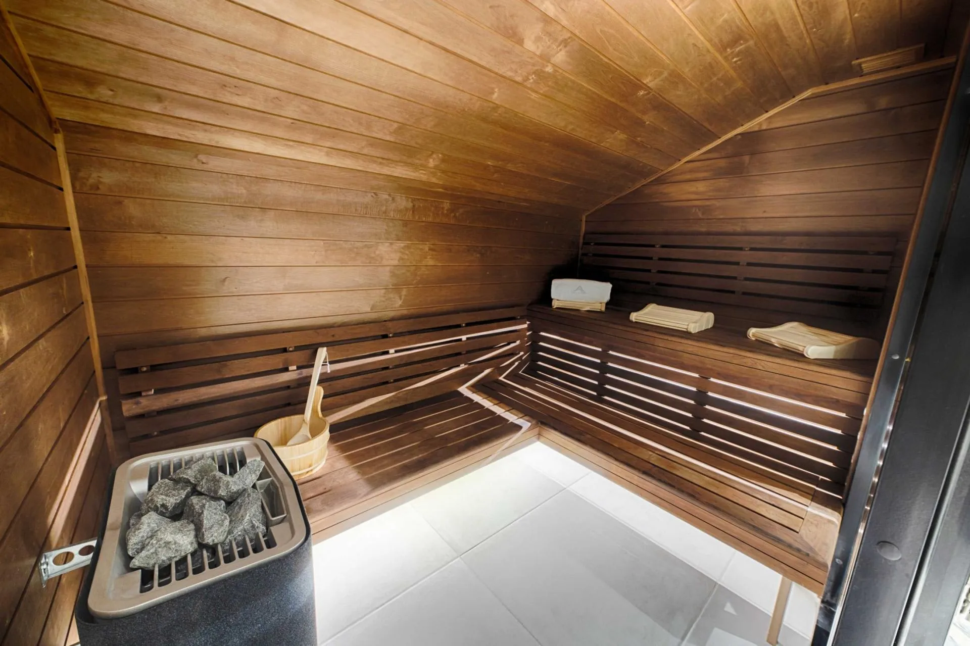 Private sauna with tiered bench seating and electric rock heater