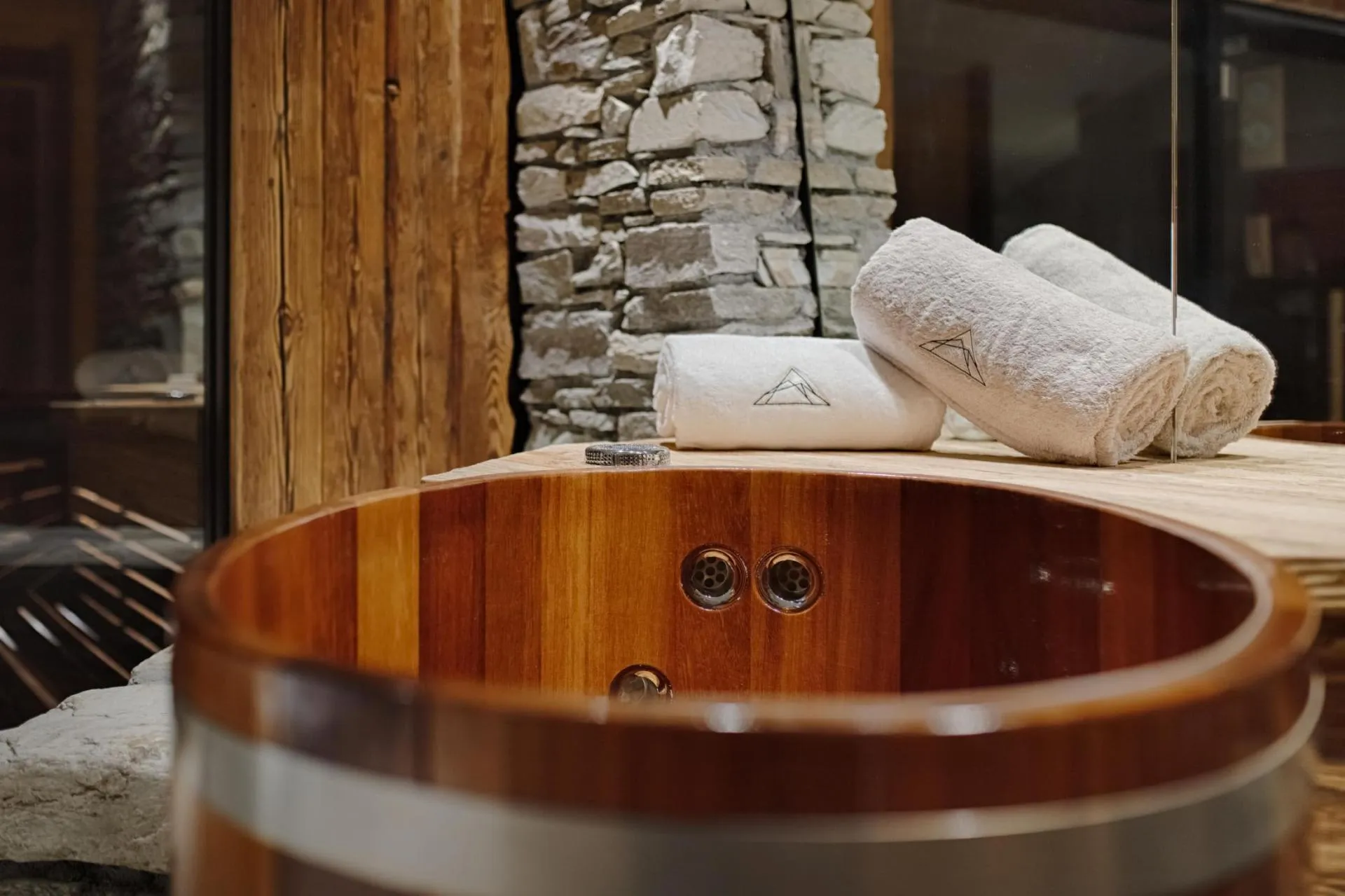 Wooden soaking tub with integrated jets and stone wall accents