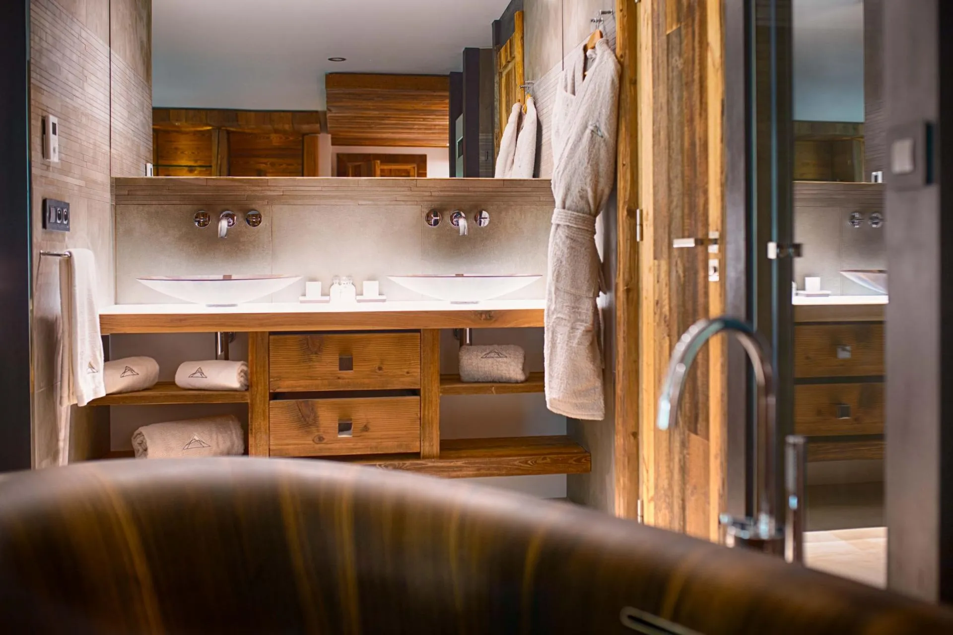 Bathroom with dual vessel sinks and wood-finished soaking tub