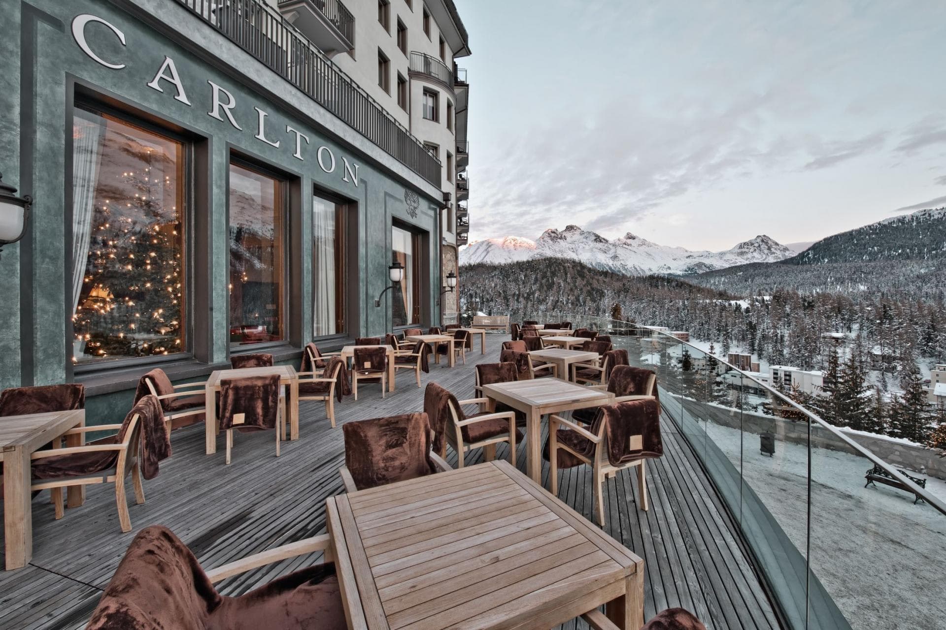 Hotel terrace with faux-fur chair throws and panoramic alpine views