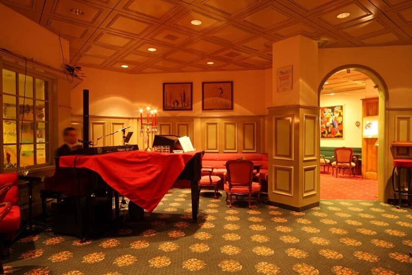 Lounge area with grand piano and wood-paneled coffered ceilings