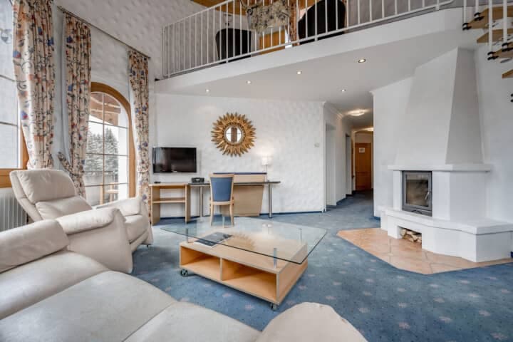 Living area with wood-burning fireplace, workspace, and mezzanine loft access