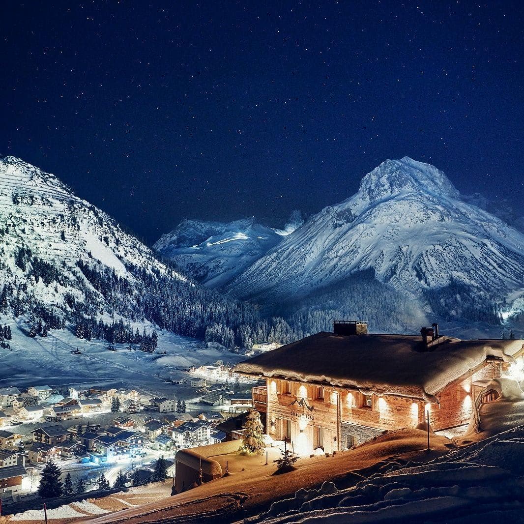 Chalet exterior with mountain valley views and village lights at night