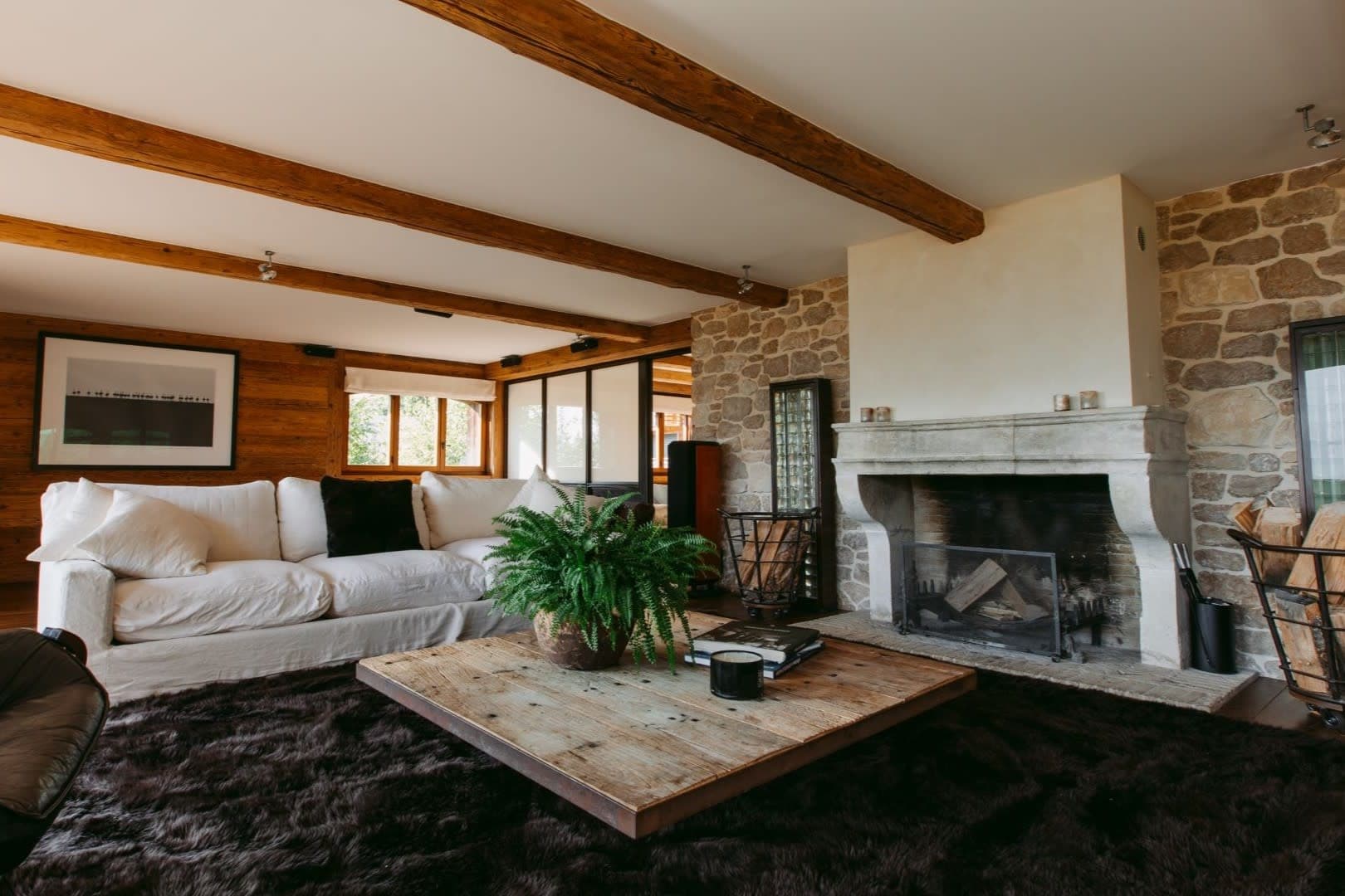 Living area with wood-burning stone fireplace and exposed timber beams