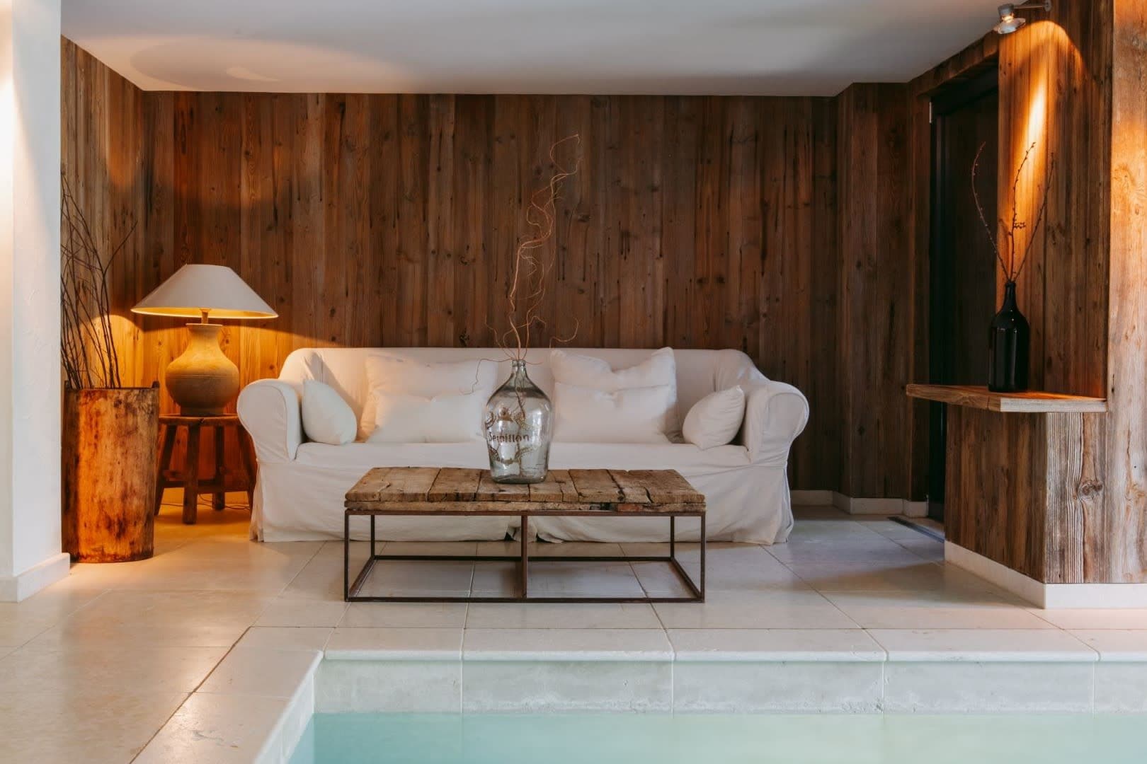 Poolside lounge area with reclaimed wood paneling and stone tile flooring