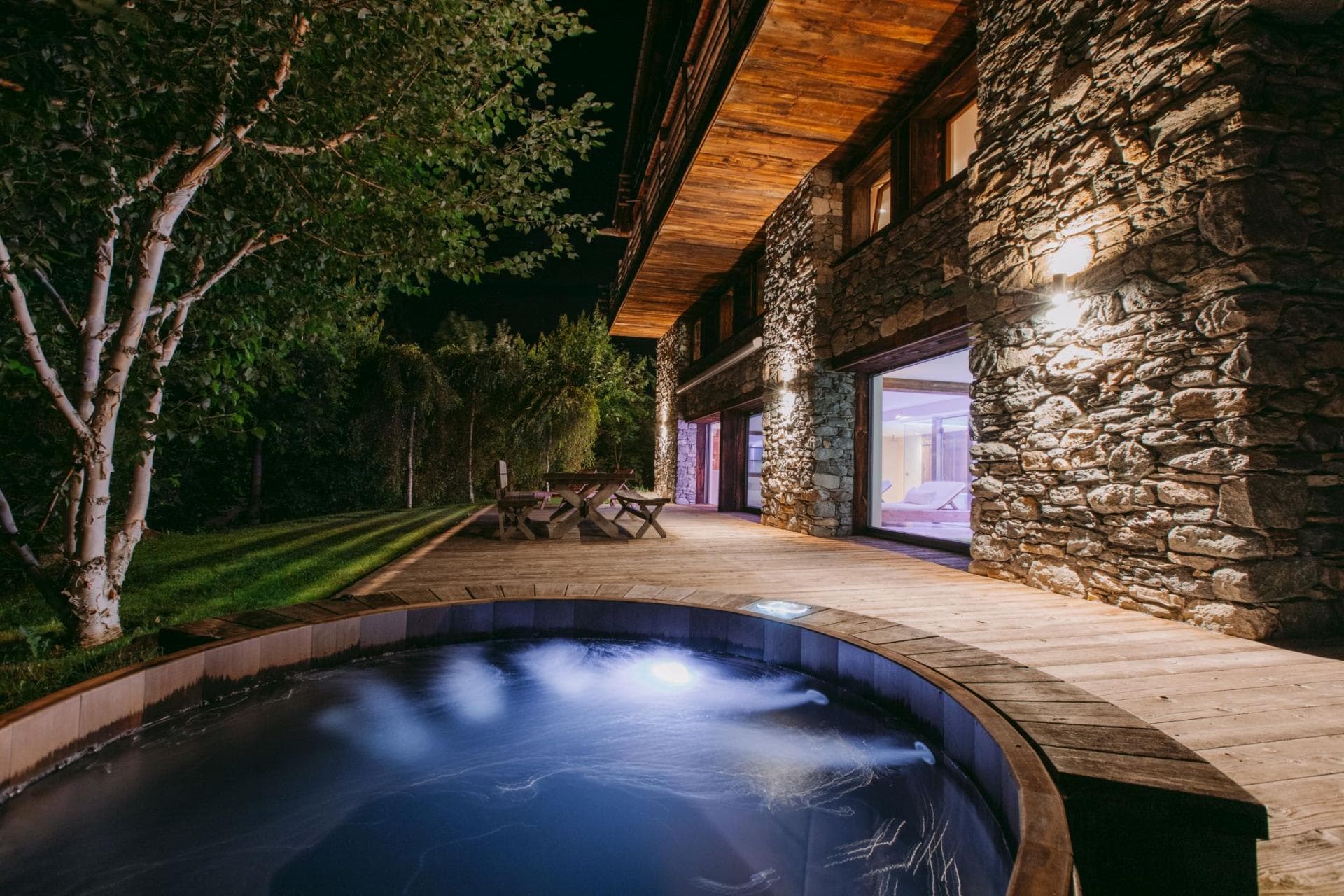 Sunken hot tub on deck with stone exterior and dining area