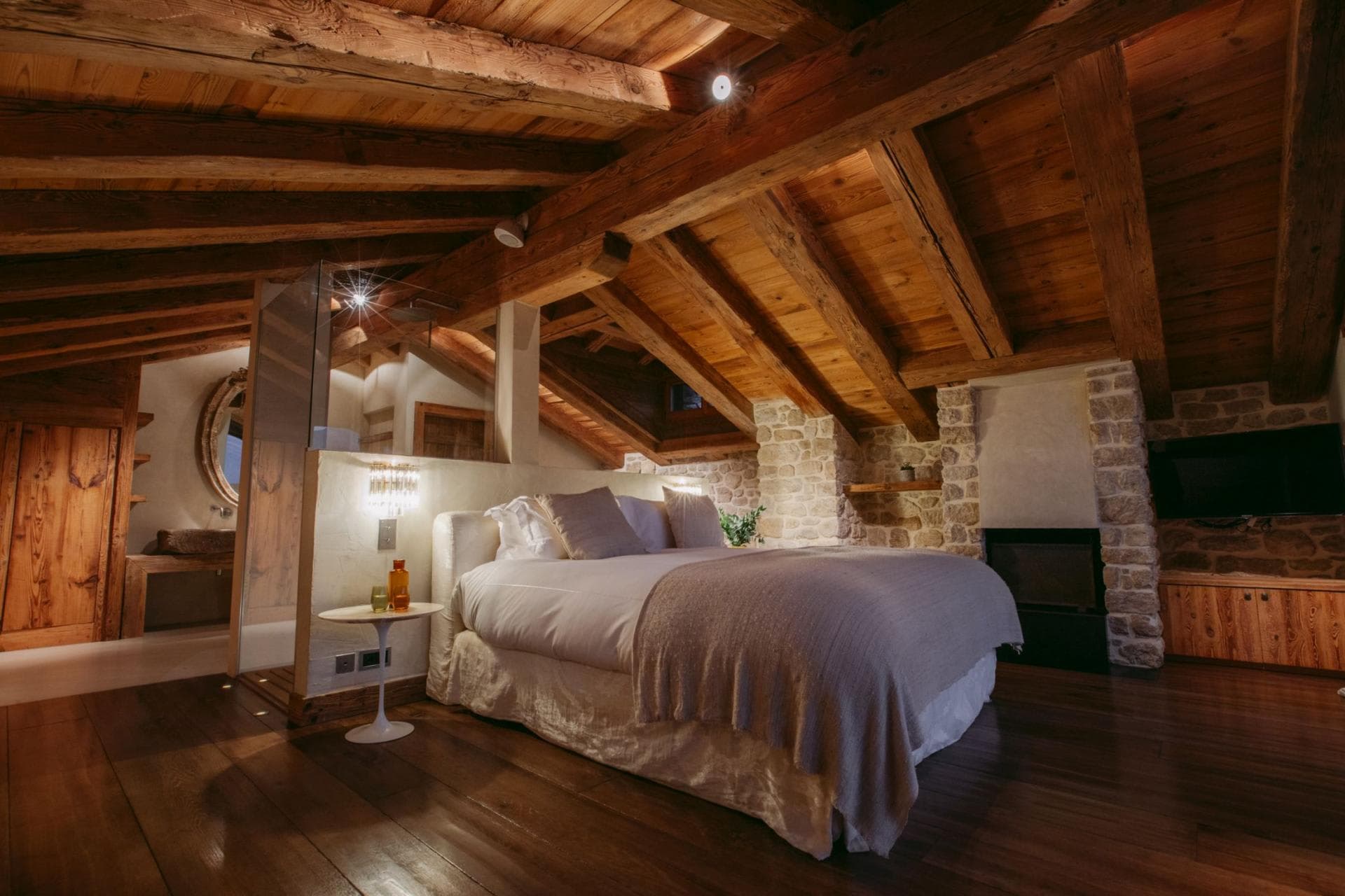 Primary suite with king bed, stone fireplace, and timber ceilings